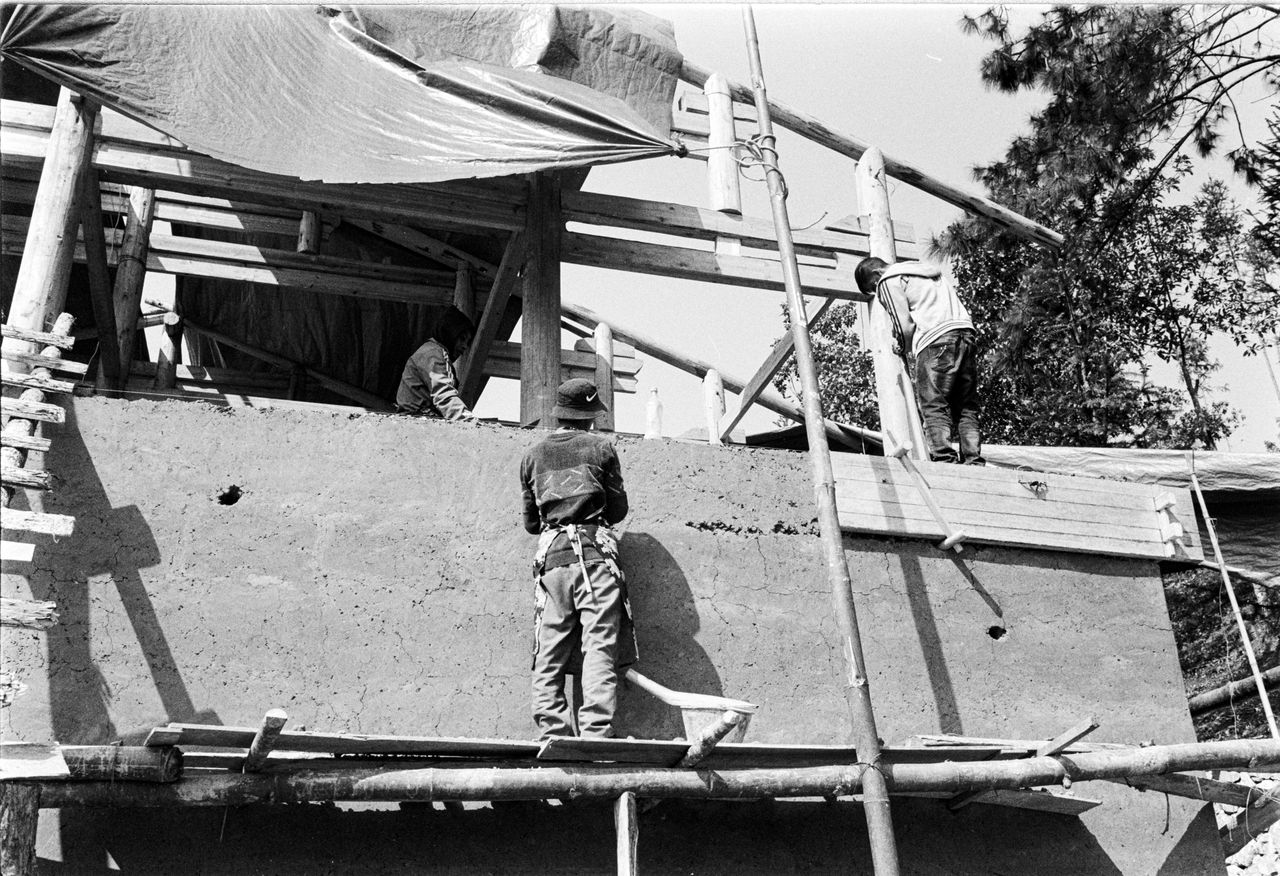 ours-journey Monochrome image of workers at a construction site with scaffolding.