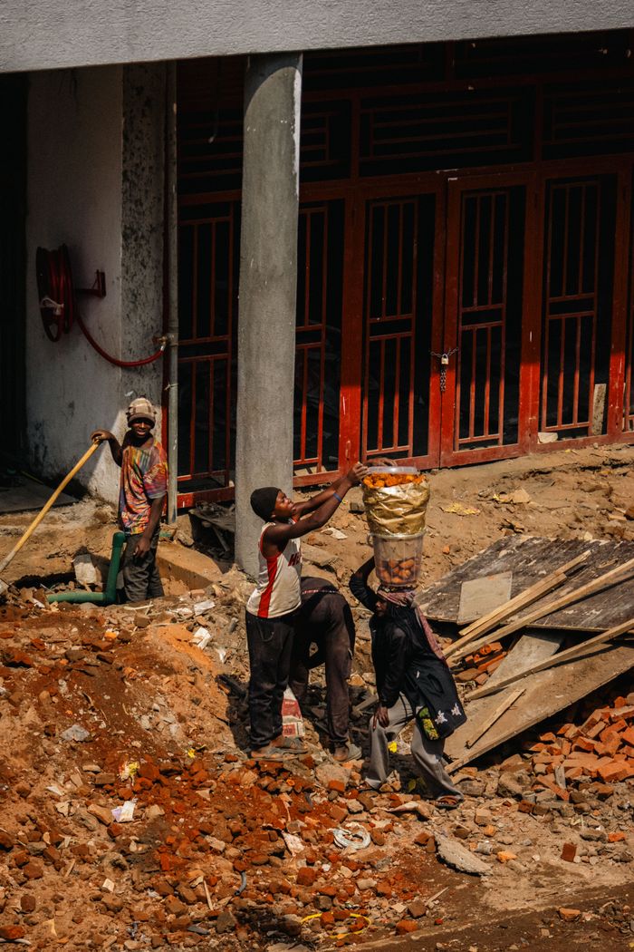 our-experience A group of construction workers engaged in manual labor on a city building site.